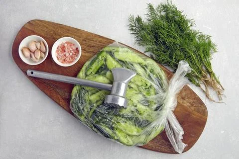 Broken salted cucumbers in a plastic bag on a wooden cutting board with a kit Stock Photos