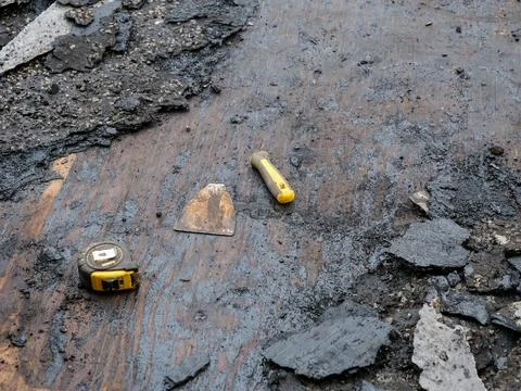 Broken scraper tool and tape measure on old flat roof Stock Photos