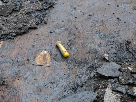 Broken scraper tool during scraping off old roofing felt Stock Photos