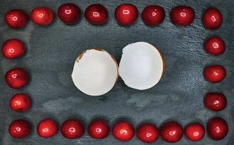 Broken shell on a black background framed with cherries Stock Photos