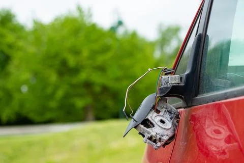 Broken side mirror on red car after accident Photos