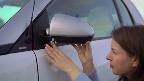 Broken off side rearview mirror on car. Woman is checking for damage on her auto Vidéo 161037757