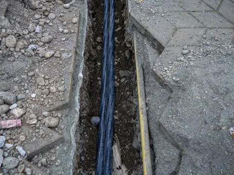 Broken sidewalk. Conducting the cable underground. Cable laying work. Commu.. Stock Photos