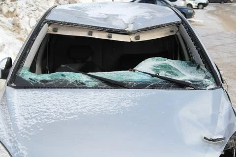 A broken silver car after an accident on the road. Broken windshield close up Stock Photos