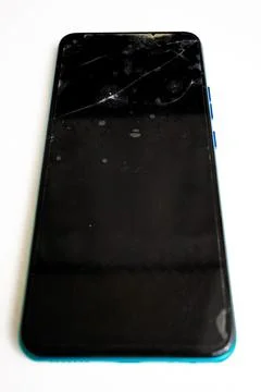 Broken smartphone lying on a white surface with visible damage Stock Photos