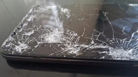 Broken smartphone screen with multiple spiderweb cracks on black glass Stock Photos