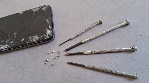 Broken smartphone screen with small metal screwdrivers and tiny screws Stock Photos