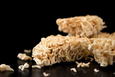 A broken square instant noodles placed on a dark brown wooden table on a blac 库存照片