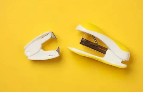Broken stapler with yellow background and staples inside Stock Photos
