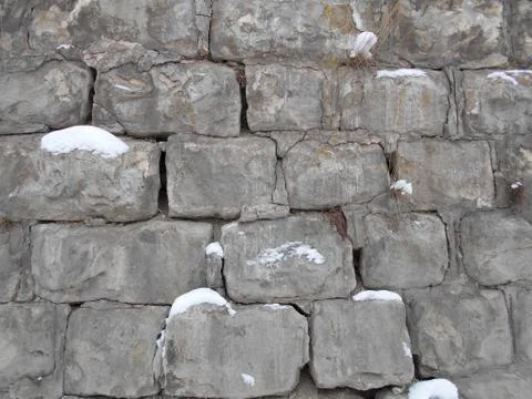 Broken stone wall in the snow. cement in the winter in the cold Stock Photos