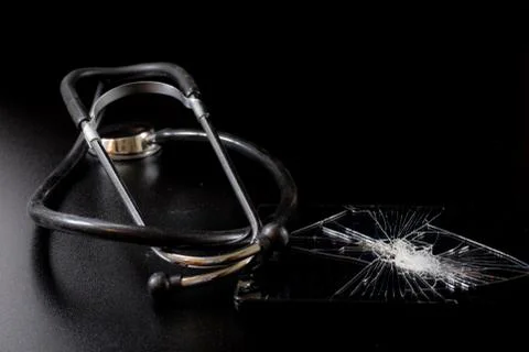 Broken tablet with broken screen and stethoscope in repair. Black table. Stock Photos