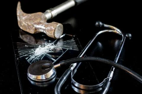 Broken tablet with broken screen and stethoscope in repair. Black table. Stock Photos