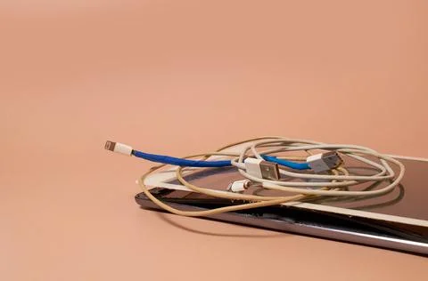 A broken tablet with a swollen battery and two bare USB wires Stock Photos