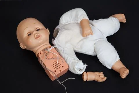 Broken talking doll on a black background Stock Photos