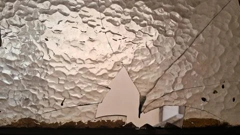 Broken textured glass pane with sharp jagged edges and holes Stock Photos