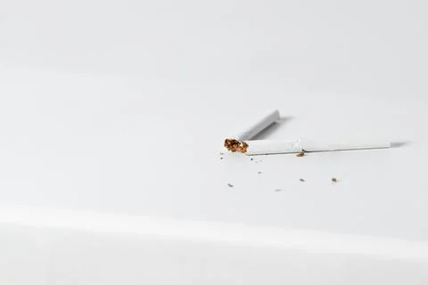 A broken thin cigarette with a white filter on the windowsill. Stock Photos