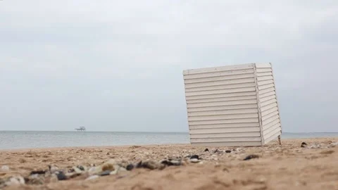 A broken tilted changing room stands on the beach in cloudy weather Stock Footage 156394170