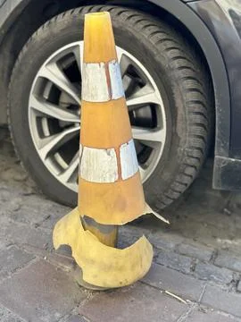 Broken Traffic Cone in Front of Car Wheel on City Street Stock Photos