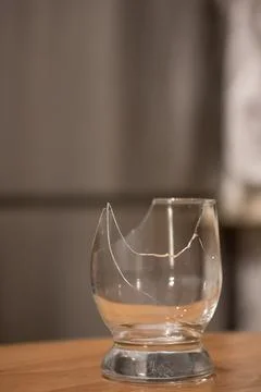 Broken transparent drinking glass on the table Stock Photos