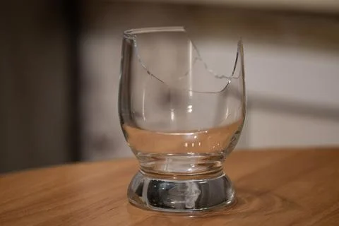 Broken transparent drinking glass on the table Stock Photos