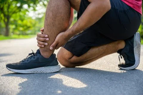 Broken twisted ankle. Runner touching foot in pain due to sprained ankle Foto stock