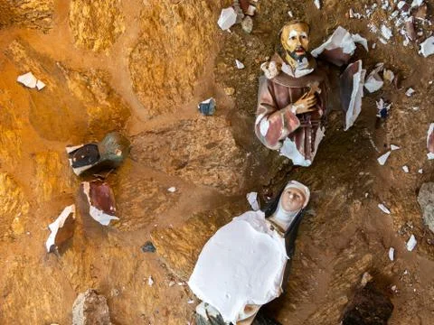 Broken vandalized plaster catholic plaster statues in the ground Stock Photos