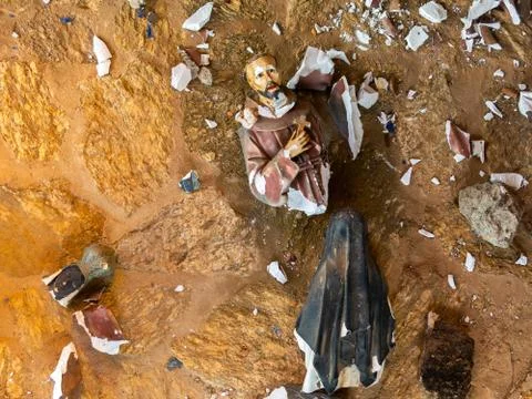 Broken vandalized plaster catholic plaster statues in the ground Stock Photos