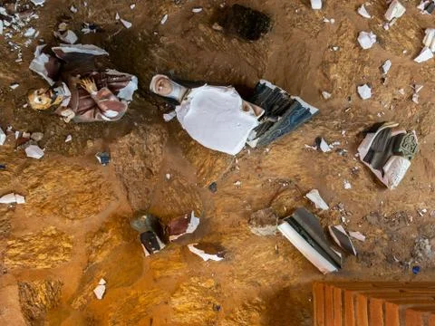 Broken vandalized plaster catholic plaster statues in the ground Stock Photos