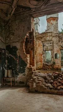 Broken wall with fallen bricks inside an old abandoned building. Stock Photos