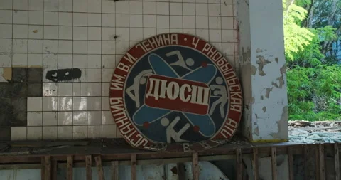 Broken wall of the gym, where a large analog wall clock and a Soviet poster hang 스톡 동영상 196569431