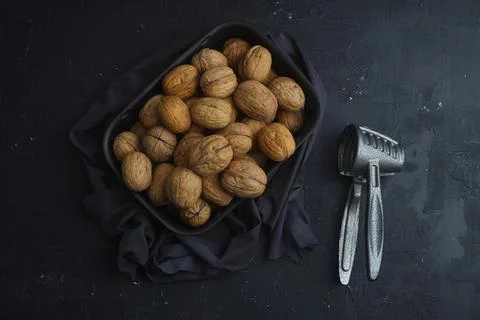 Broken walnuts and nutcracker on black background Foto stock