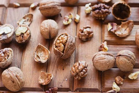 Broken walnuts on a wooden background. split nuts near the nutcracker Stock Photos