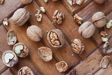 Broken walnuts on a wooden background. split nuts near the nutcracker Stock Photos