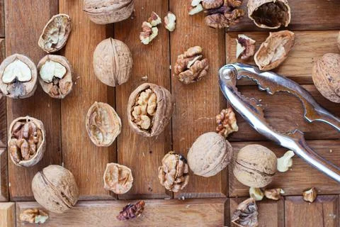 Broken walnuts on a wooden background. split nuts near the nutcracker Stock Photos