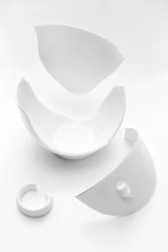 Broken white cup on a white background. Vertical. Concept of carelessness. Mu Stock Photos
