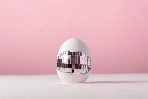 Broken white egg exposes mirrored disco tiles, playful pastel still life for Fotos Stock