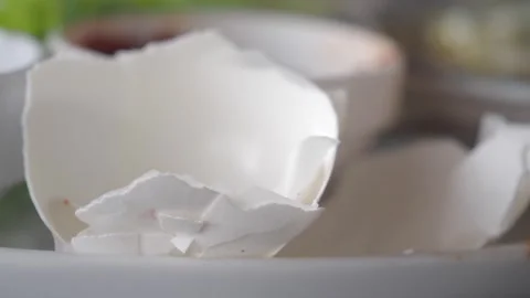 Broken white eggshell fragments on plate close up cinematic macro kitchen b.. Stock Footage 331905291