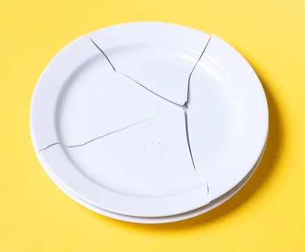 Broken white plate on a solid background 库存照片