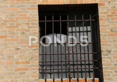 Broken window of an abandoned house with iron bars Stock Photos