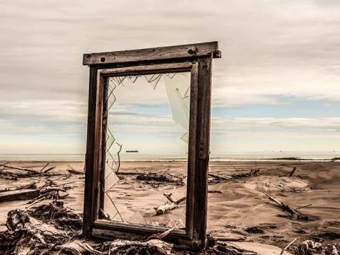 Broken window on a deserted beach overlooking the sea and the silhouette of a Stock Photos