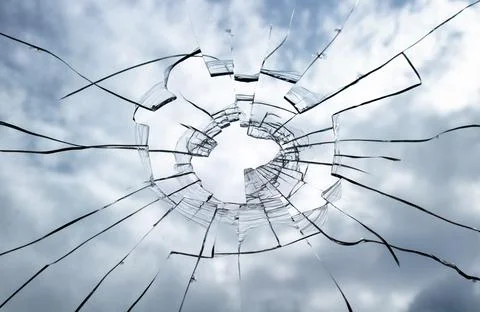 Broken window glass on a background of cloudy sky. Stock Photos