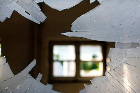 Broken Window Glass looking inside a House with a window background opposite Stock Photos