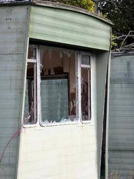 Broken window on a pale green mobile home Stock Photos