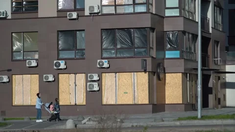 Broken windows of a residential building, clogged with plywood and plastic wrap Stock Footage 194495911
