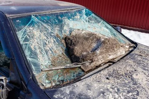 Broken windshield covered in snow and debris. Wiper lies shattered beside c.. Stock Photos