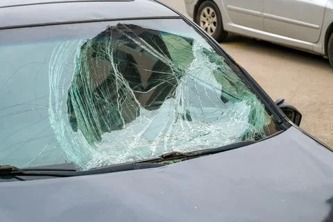 Broken windshield of damaged car after accident in city street. Damaged car w 库存照片