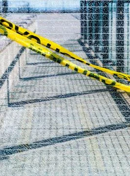 Broken wired mesh glass panel with diagonal yellow caution tape. Stock Photos