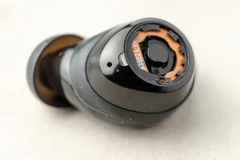 Broken wireless earbud resting on a clean surface in quiet morning light 스톡 사진