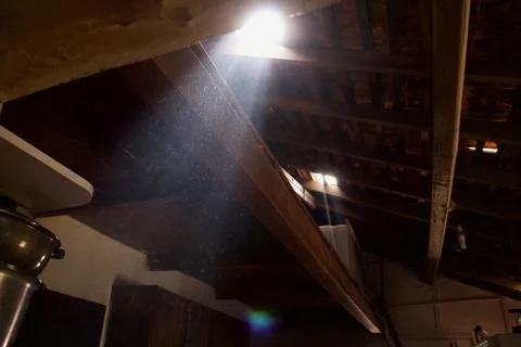 Broken wooden ceiling casting sunlight through a hole. Stock-Fotos