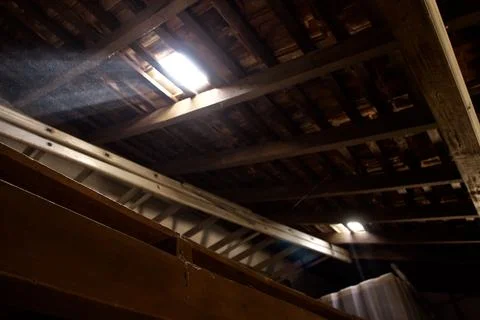Broken wooden ceiling casting sunlight through a hole. Stock Photos